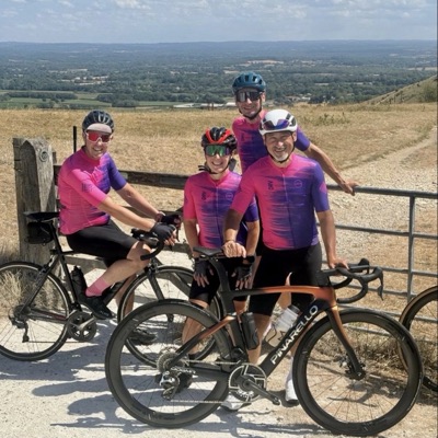 Dawn Raid Velo riders in the pink and purple kit at a hilltop gate
