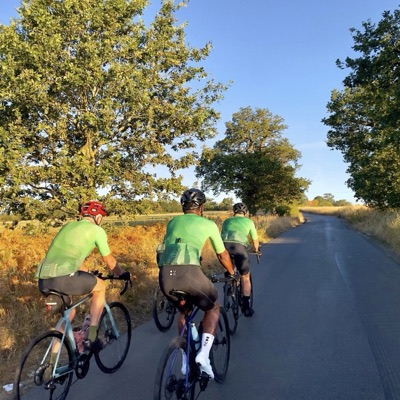 Three Dawn Raid Velo riders in the green kit on a lane at dusk