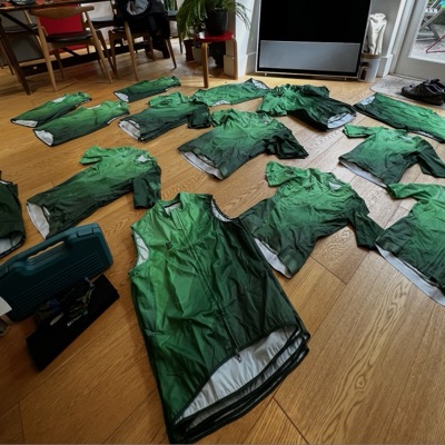 A finished run of green Dawn Raid Velo jerseys and gilets laid out